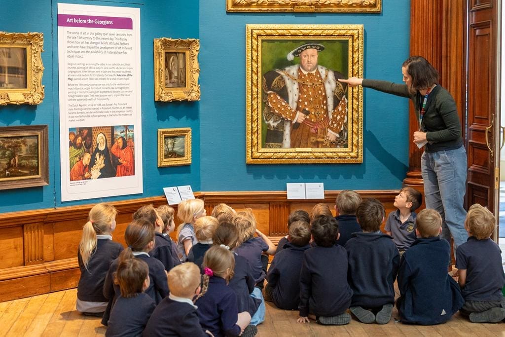 school group sitting in the floor looking at a number of paintings on the wall