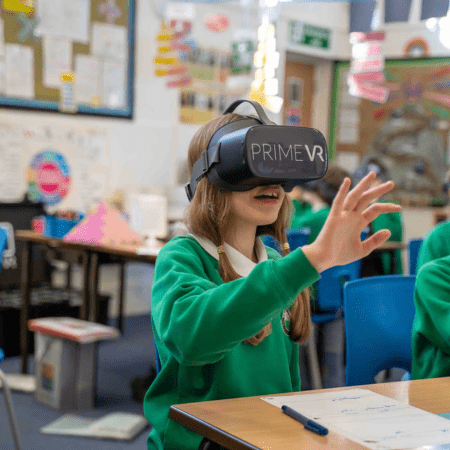 school pupil waving with headset on in class room