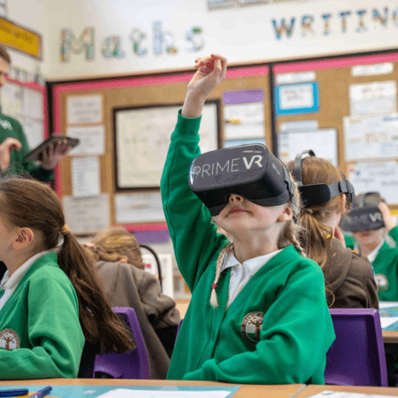 school pupil with VR headset on with hand up