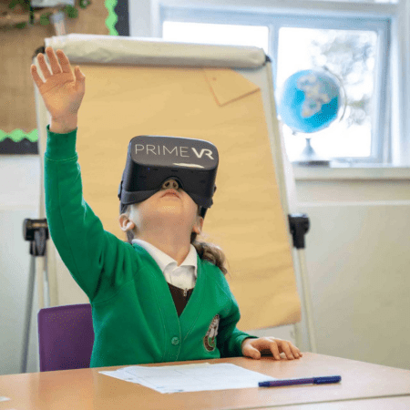 school pupil with VR headset waving in class