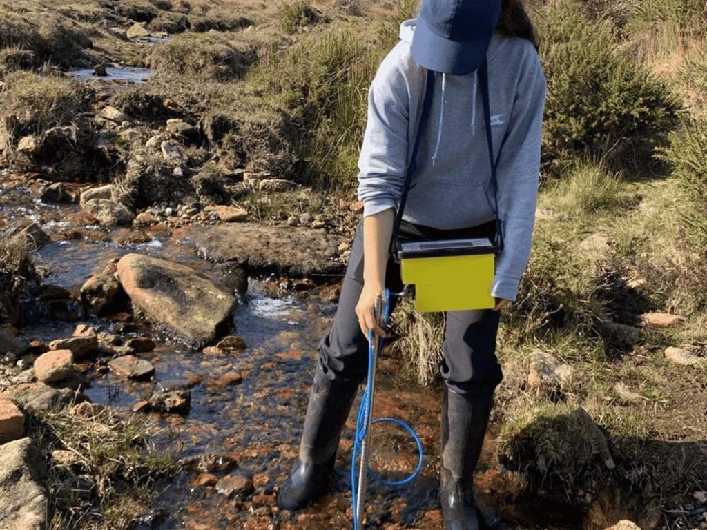 school trip pupil in a stream doing field work to monitor water quality