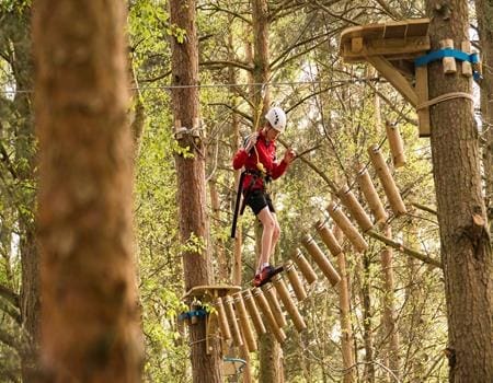 school student with safety gear and hard hat on high ropes