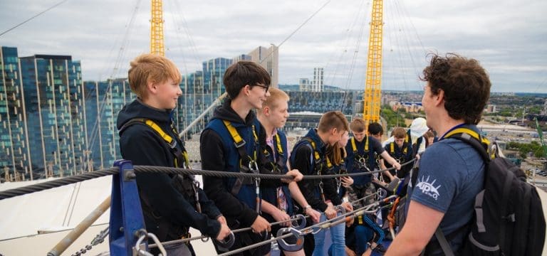 school group standing on top of the O2 in London with safety equipment attached to a safety line