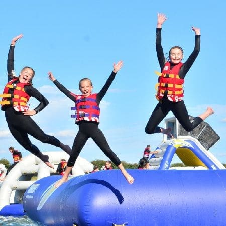 primary school pupils jumping off a object onto a lake of water