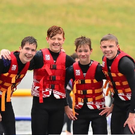 school group having a photo taken with wetsuits on smiling