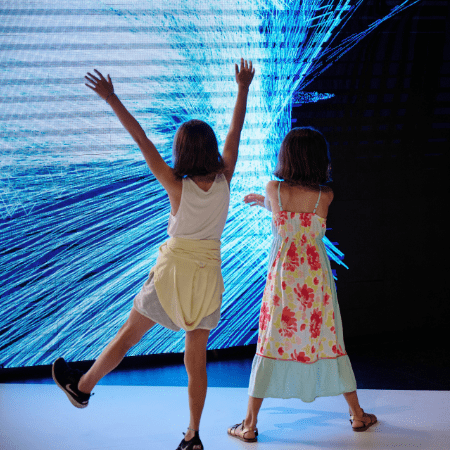 two primary school pupils watching interactive exhibition screen