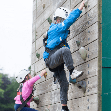 students climbing up a climbing outdoor climbing wall