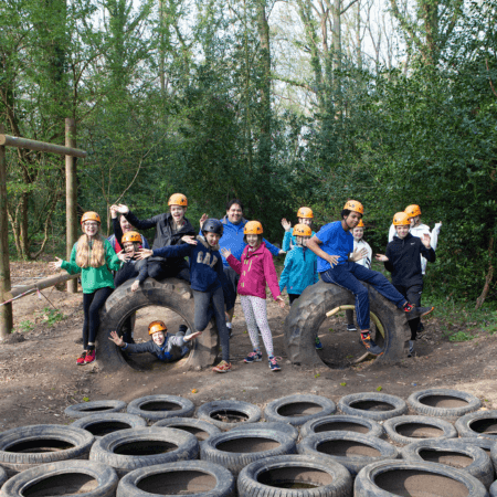 school group in hard hats near an outdoor assault course in the countryside