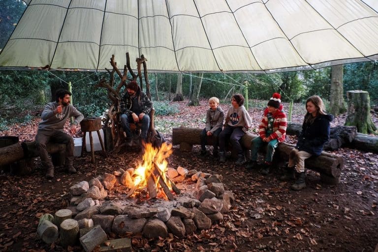 primary pupills around an open fire pit outside in the forest with the wilderness centre
