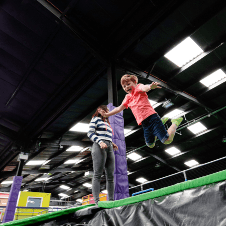 school pupil jumping off a ledge onto a trampoline below