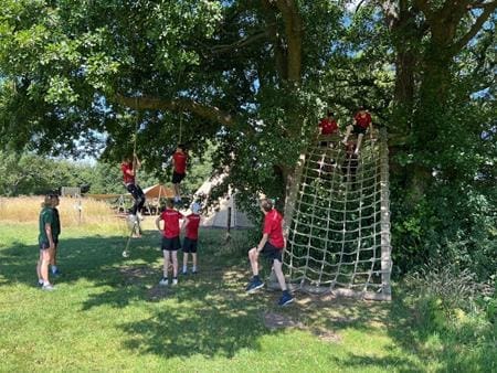school pupils going down a rope course outside in a field