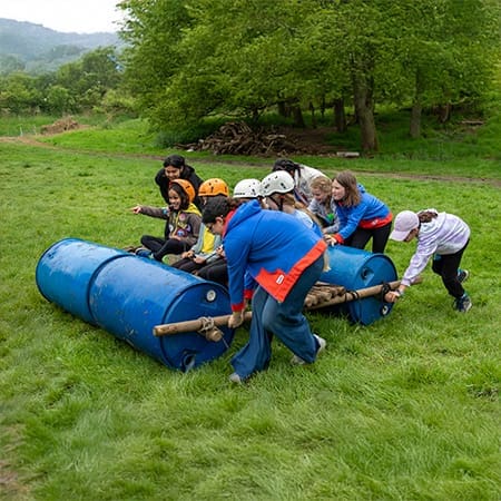 school pupils making a wooden raft from plastic barrels and wooden logs