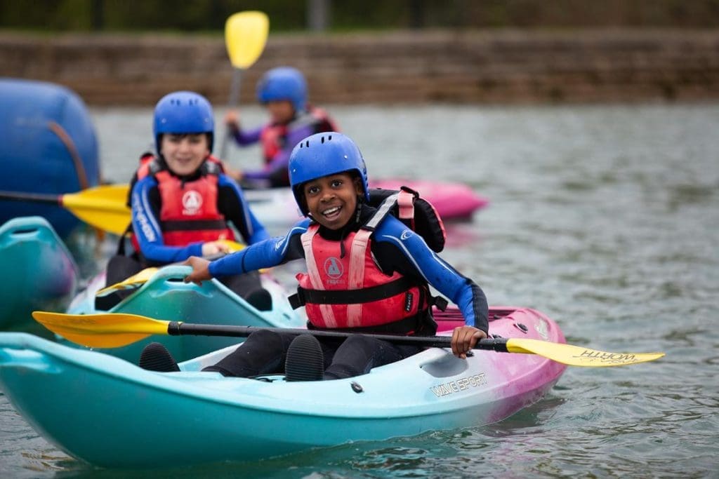 group of pupils on a lake with kayaks and paddles