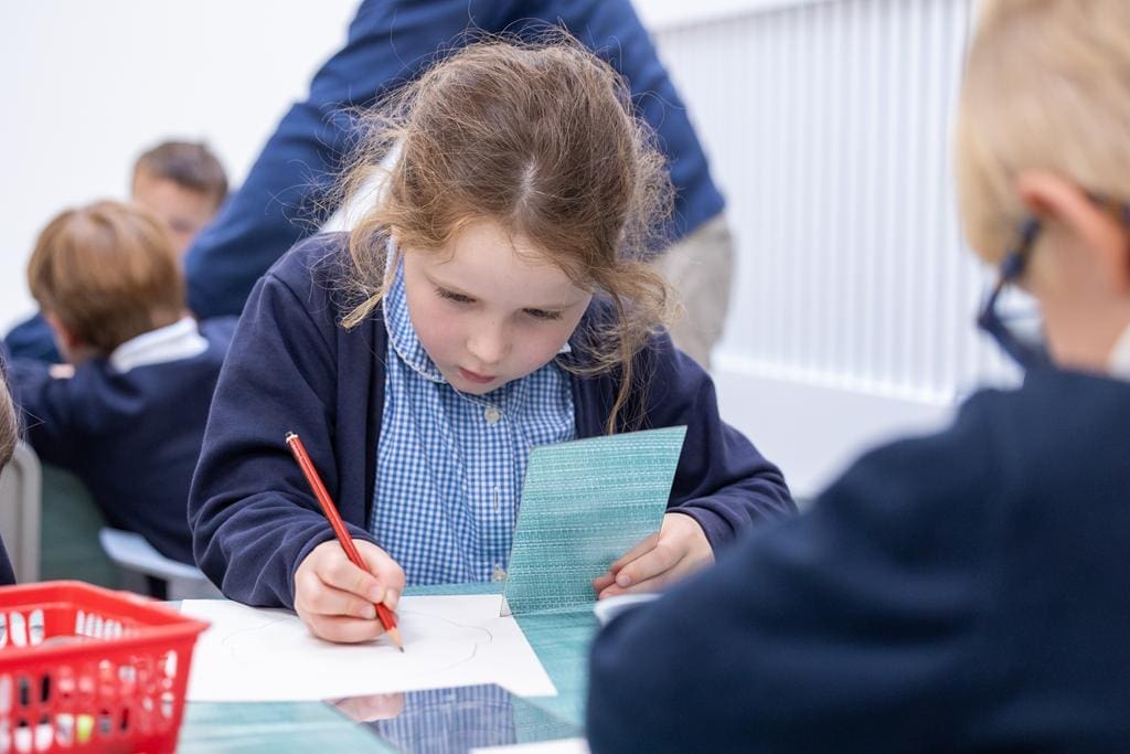 school pupil with paper and crayons drawing at workshop