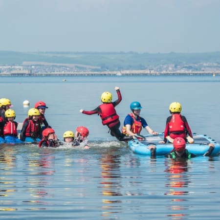 primary school children on paddle boards on a lake