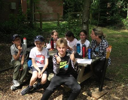 school trip group in a forest doing bushcraft