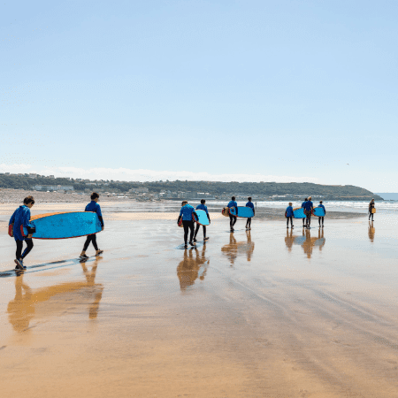 school group walking at the beach with surf boards