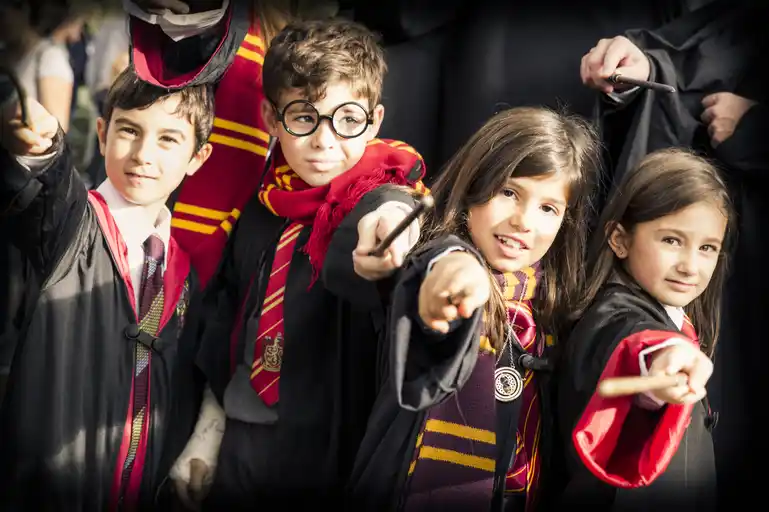 four school pupils with wizard sticks and dressed as harry potter for a group photo