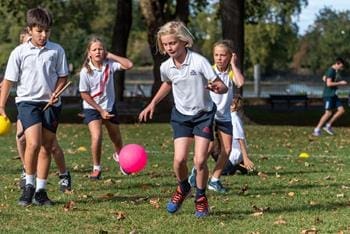 school group playing football on a pitch