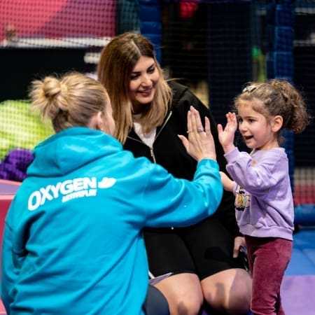 image shows a primary school pupil high fiving an instructor at Oxygen indoor play adventure park