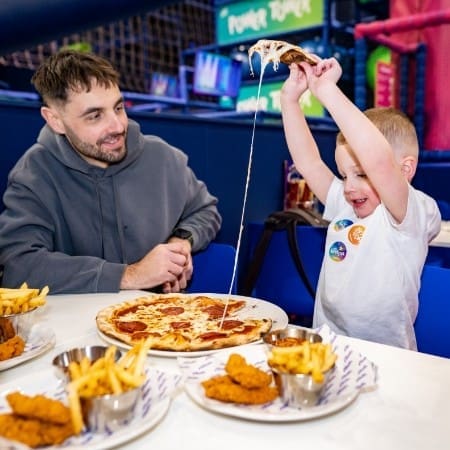 image shows pupil eating pizza in a indoor play adventure park canteen area