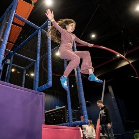image shows secondary school pupil jumping off a padded indoor adventure play park