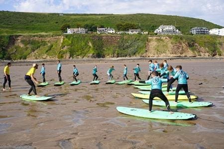school pupils at the beach doing surf board training