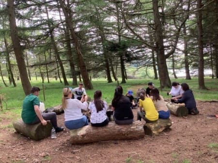 school group around an open fire in the woods