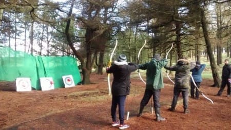 secondary school trip pupils doing archery on a wooded range